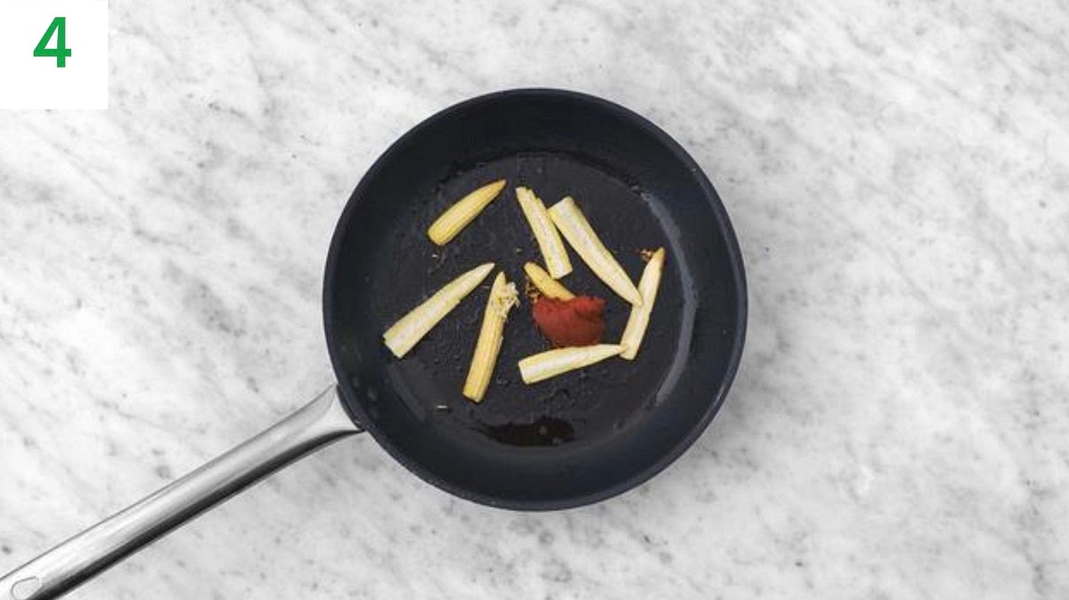 Heat a drizzle of oil in a large frying pan on medium-
high heat.
Once hot, add the baby corn.
Stir-fry until tender, 5-6 mins. Continue to stir while it cooks.
Stir in the red Thai style paste and the garlic. Cook, stirring, for 1 min more.