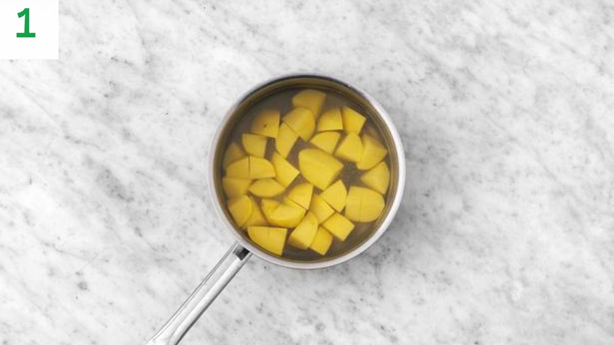 Preheat your oven to 220°C/200°C fan/gas mark 9. Boil a full kettle.
Remove the lamb steaks from your fridge to allow them to come up to room temperature.
Pour enough oil into a deep baking tray to cove the bottom and pop into the oven. Peel and chop the potatoes into 3cm chunks.
Pour the boiled water into a large saucepan on high heat with ½ tsp salt. Boil the potatoes for 5-6 mins or until the edges are so .