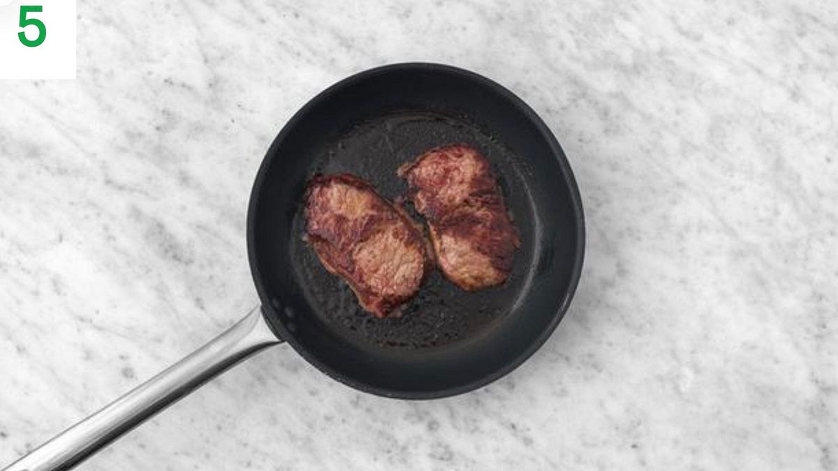 Once the broccoli is in the oven, heat a drizzle of oil in a large frying pan on high heat. Season the steaks with salt and pepper. TIP: Lamb steaks naturally vary in shape, so adjust the following timings depending on how you like yours cooked.
Once hot, lay the steaks into the pan and fry until browned and medium-rare, 8-10 mins total. Turn every 2 mins. TIP: Cook each side for 1-2 min more if you like it more well done.
Once cooked, transfer to a board, cover with foil and allow to rest for a couple of mins.