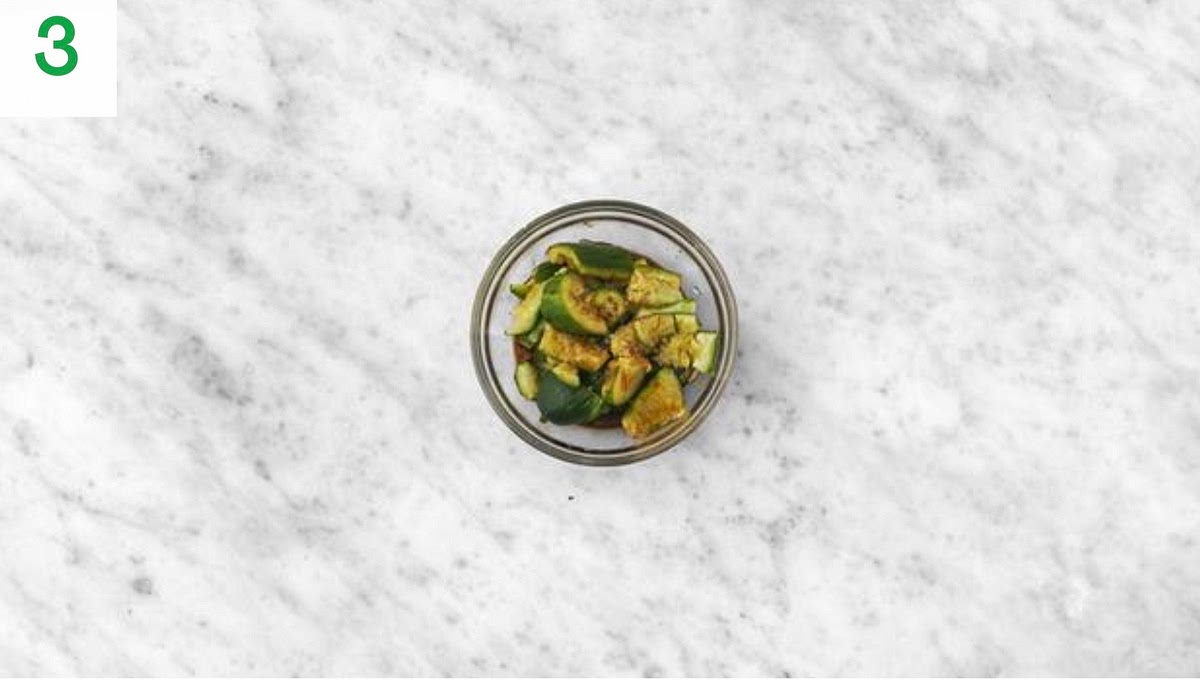 Meanwhile, peel and grate the garlic (or use a garlic press).
Trim and thinly slice the spring onion. Halve the lime.
Trim the cucumber, then pop onto a board and use a rolling pin to gently smack it a few times until split. Cut into roughly 2cm chunks.
In a small bowl, combine a good squeeze of lime, the sugar for the dressing and half the soy sauce. Add the cucumber and toss to coat. Set aside for later.
