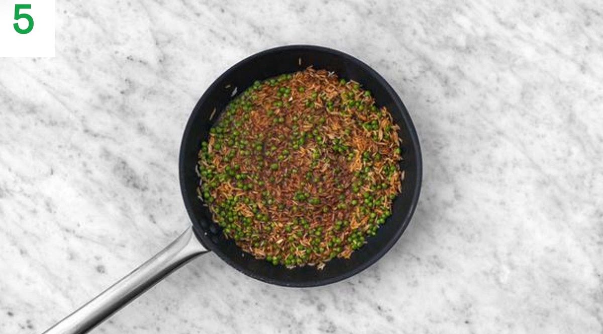 Once thickened, stir the cooked rice and peas through the sauce until combined and piping hot.
Add in a good squeeze of lime juice. Taste and season with salt, pepper and more lime if needed.