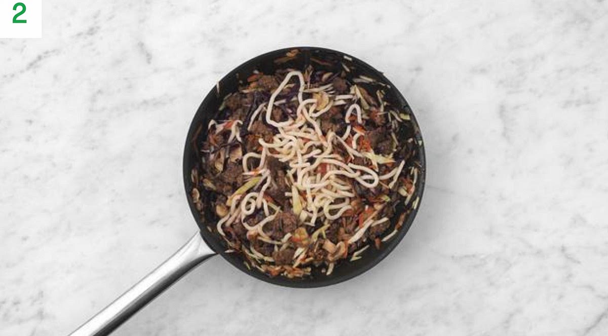 Next, add the sliced carrot and cabbage mix. Stir-fry, 1-2 mins.
Add the udon to the pan. Toss to coat, using a fork to gently separate them.
Stir-fry, 1 min more.