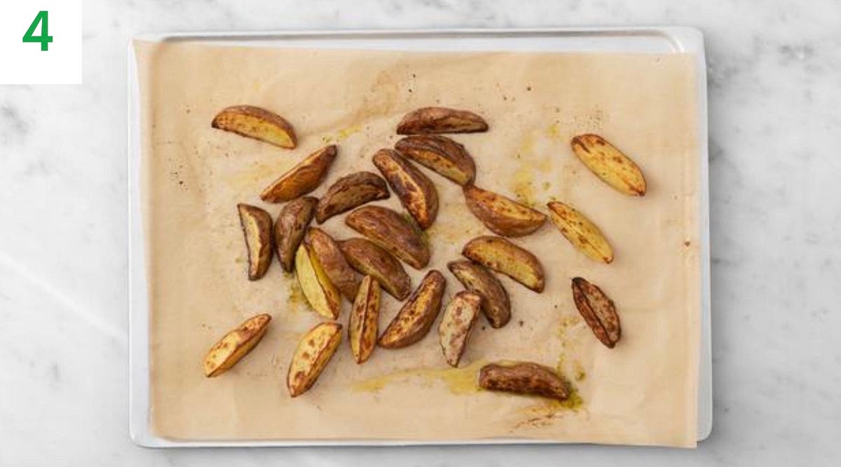 Meanwhile, zest andcut thelime into wedges. In a small bowl, combinethelime zest, honey and olive oil for the dressing.
Season with salt and pepper, then mix well.
When the wedges have 5 mins remaining, spoon over the honey lime dressing and toss to combine. Return the wedges to the oven for the remaining cook time.