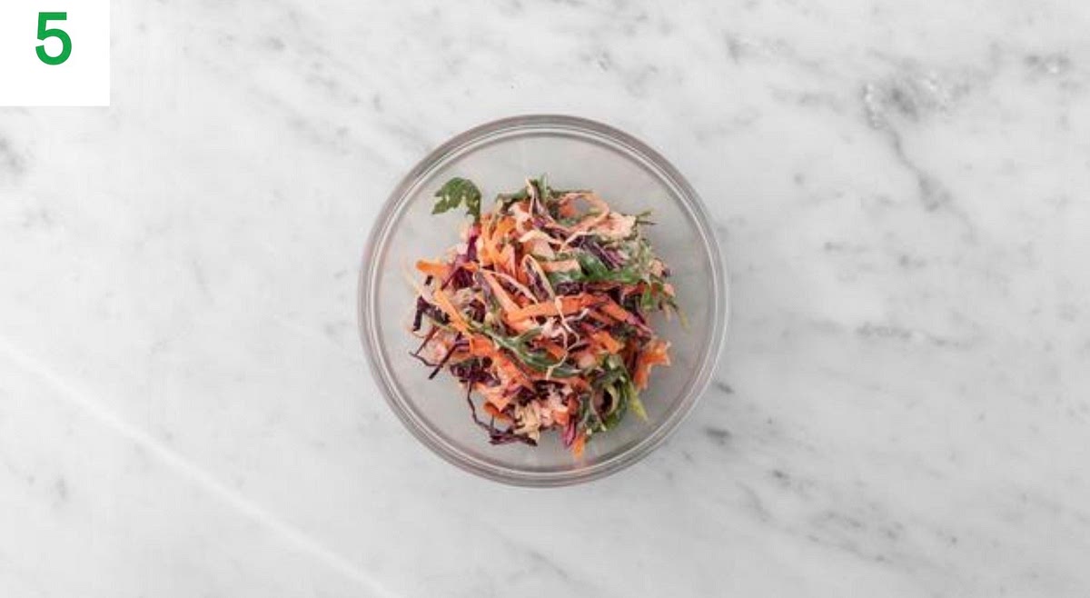 While everything cooks, in a medium bowl, combine the mayo, a squeeze of lime juice from a lime wedge and the sugar.
Add the sliced carrot and cabbage mix to the bowl of zesty mayo and stir to combine. Season with salt and pepper. Taste and add more salt, pepper or lime juice if needed.
Just before everything's ready, mix the rocket into the slaw.