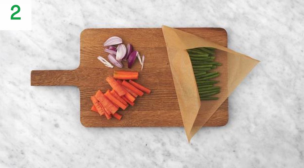 While the wedges cook, halve and peel the red onion, then cut each half into 3 wedges.
Trim the carrots, then halve lengthways. Chop into roughly 1cm wide, 5 cm long batons.
Trim the green beans. Pop your green beans onto a piece of foil with a drizzle of oil and season with salt and pepper. Toss to coat. Fold the foil, sealing on all sides to create a parcel.