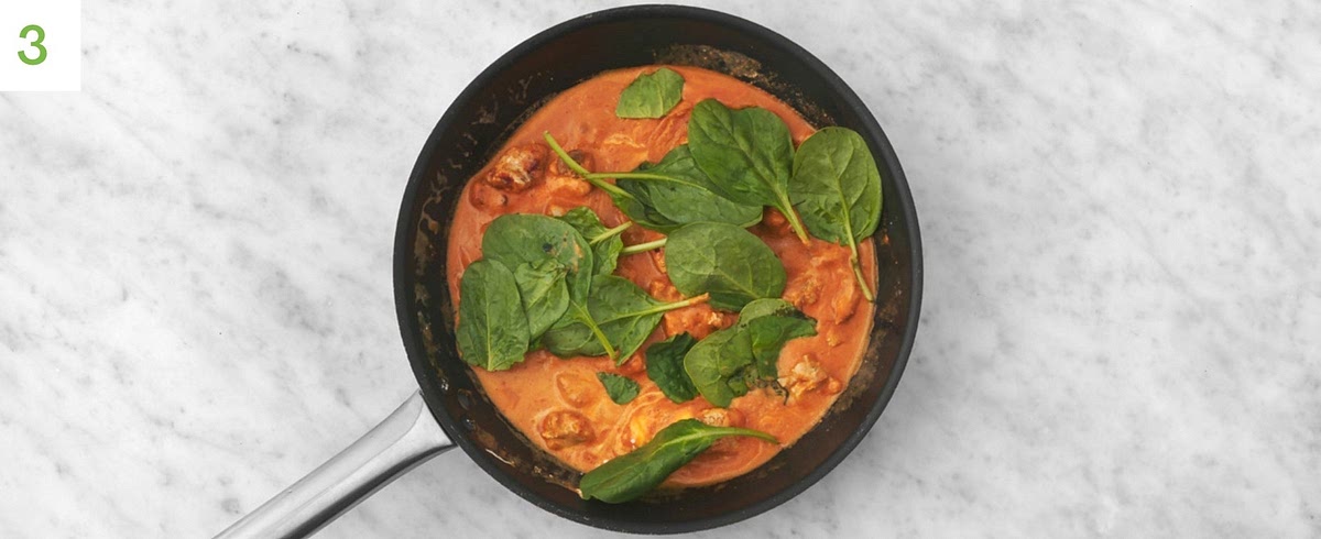 Once the chicken is cooked, stir in the tomato puree, crème fraiche, harissa (add less if you’d prefer things milder), red wine stock paste, sugar and water.
Bring to the boil, then simmer, 2-3 mins.
Add the spinach in handfuls, making sure it’s pipping hot, 1-2 mins. Stir through the cheese.