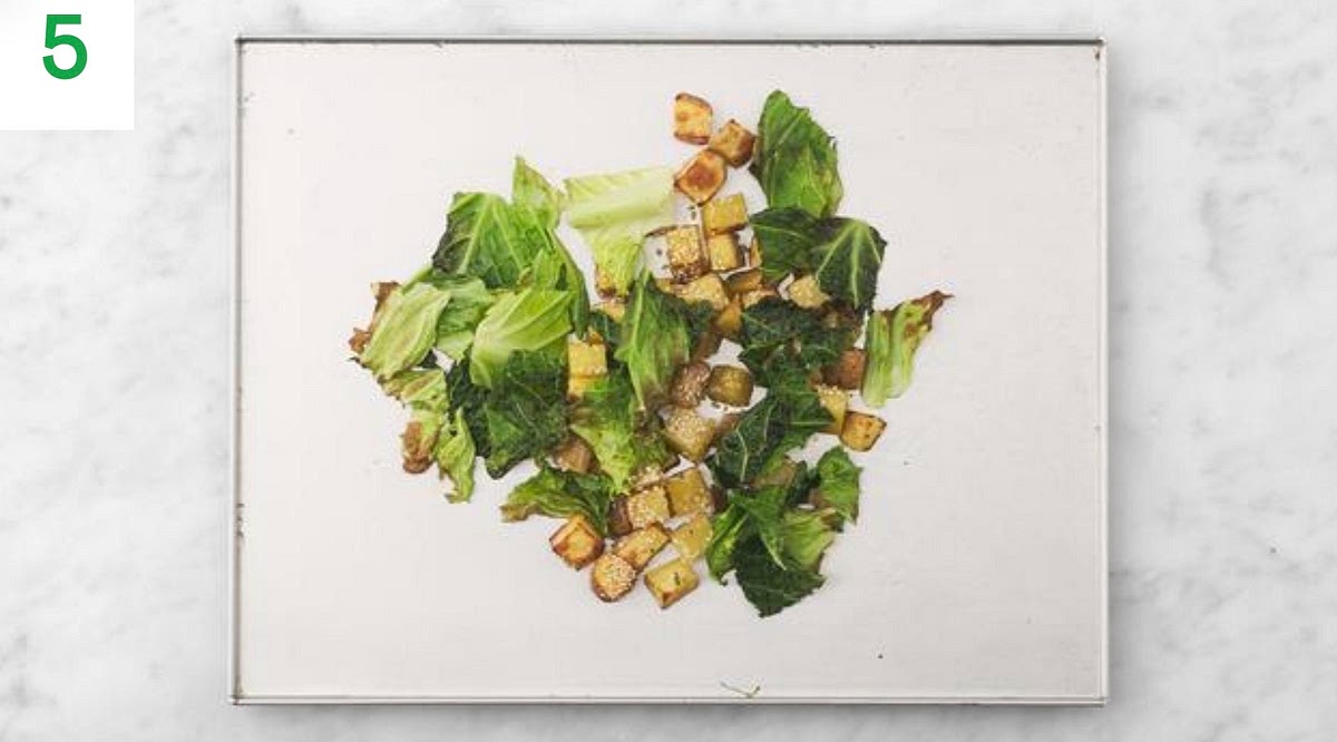 When the potatoes have 8 mins remaining, remove the tray from the oven.
Spread the kale on the other side of the baking tray, drizzle with oil and season with a pinch of salt and pepper to taste.
Return the tray to the oven for the remaining time, until the kale is crispy, 7-8 mins.