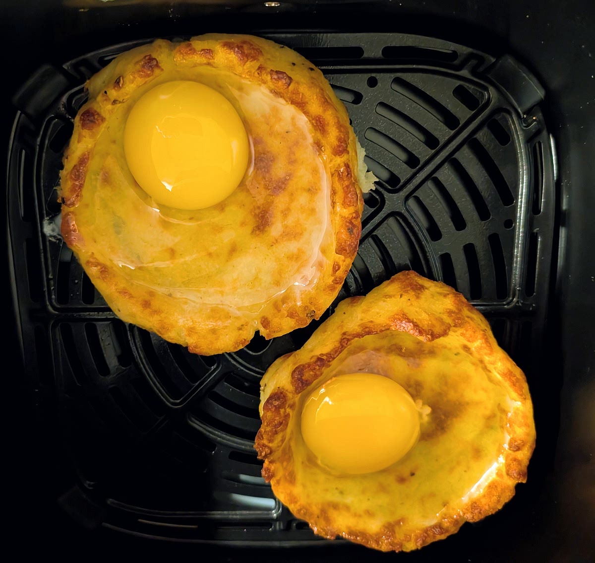 Take them out, remove the parchment paper, and put them carefully back in the air fryer. Break one egg carefully in each nest, and season the eggs to taste.