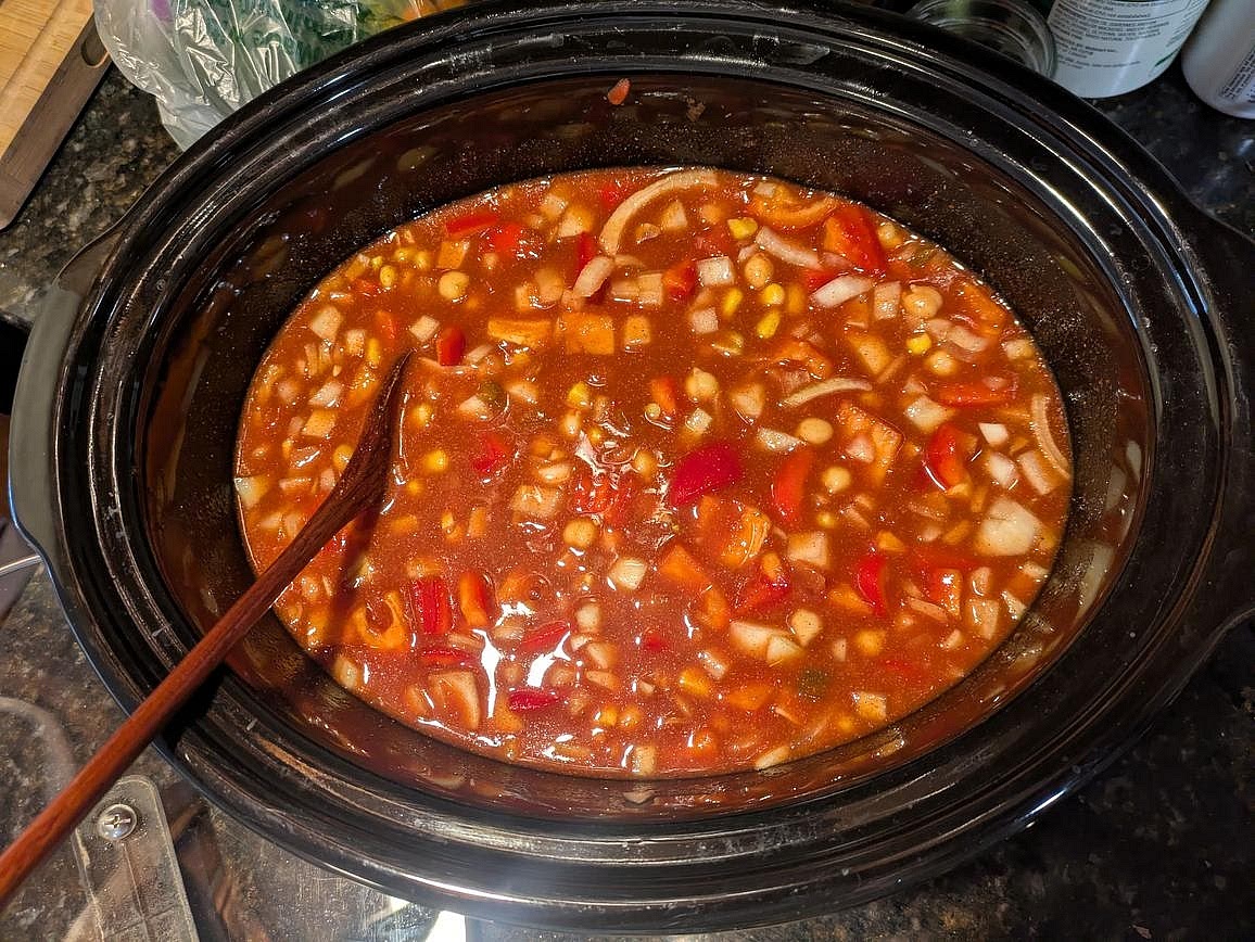 Add the rest of the ingredients into the pot - corn, lentils, broth, tomato sauce, salsa, paprika, garlic powder, cumin, and cayenne pepper