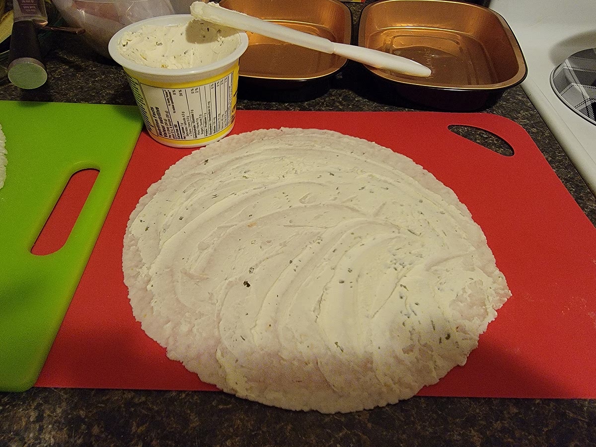 Spread cream cheese on the tortilla as close to edge as possible.