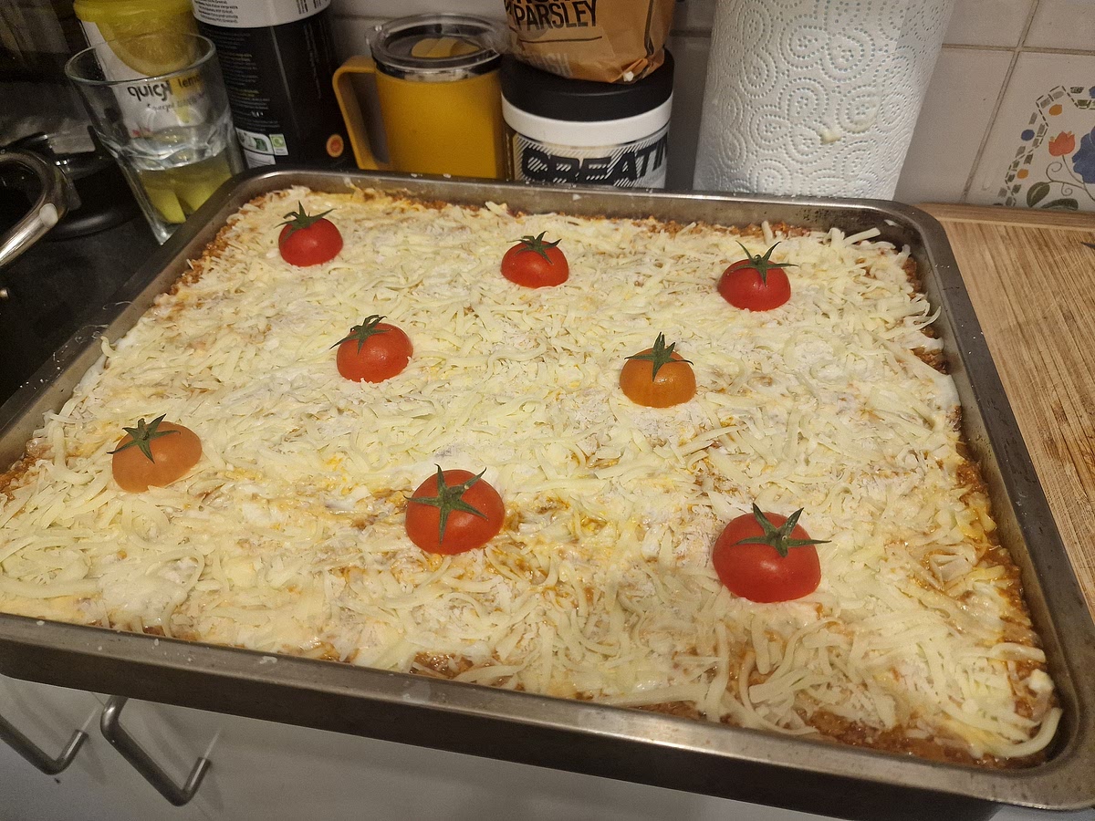 Finishing the construction: After you are done with the last layer of meat you should cover it with the rest of the bechamel sauce, grated parmesan and fresh mozzarella like before. I like to also add a layer of regular grated mozzarella to make it just a bit more cheesy. Then slice cherry tomatoes in half and place the top parts with attached vines on top of your lasagne. This is decorative and adds a bit of extra tomato flavour for a single bite when you're eating.