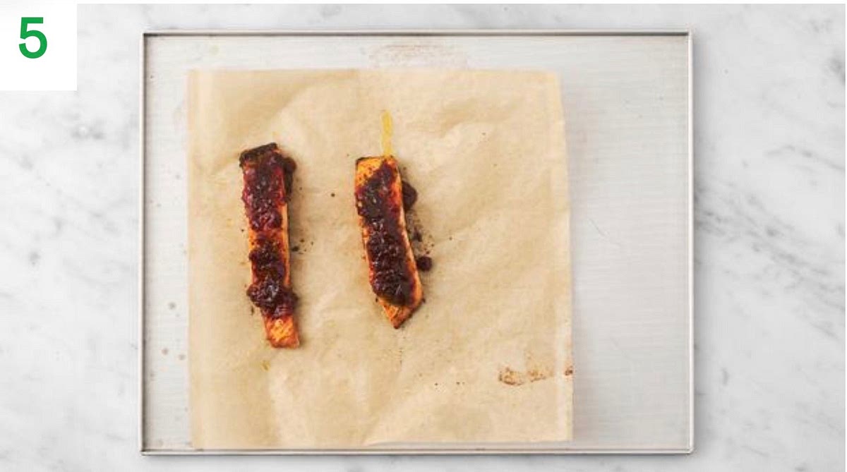 Add the yogurt to a small bowl.
Once the garlic has cooled, cut the end with scissors, squeeze it out of the skin and mash with a fork. Stir the roasted garlic into the yogurt. Season with salt and pepper.
Once cooked, drizzle half the red pepper chilli jelly over the salmon, then drizzle the remaining jelly over the veg. Toss the veg to coat.
Toss your baby leaves through the dressing.