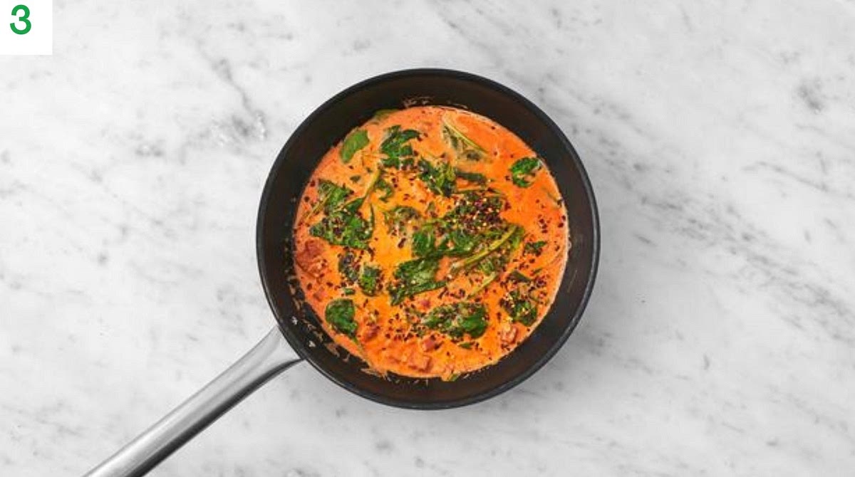 Stir in the tomato puree and half the chilli. Fry, 1 min.
Add the crème fraiche, chicken stock paste, sugar and water. Simmer, 2-3 mins.
Add the spinach in handfuls, making sure it’s piping hot, 1-2 mins.