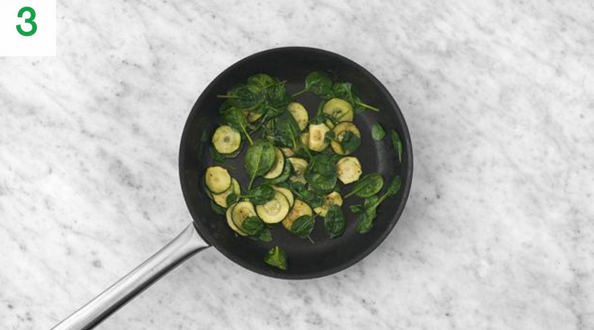 Meanwhile, heat a drizzle of oil in a large frying pan on high heat.
When hot, add the courgette and cook until charred, 3-4 mins each side.
Once cooked, lower the heat, then stir in the garlic and cook for 1 minute more. Season with salt and pepper.
Add the spinach a handful at a time and cook until wilted and piping hot, 1-2 mins. Once cooked, transfer everything to a large bowl and cover to keep warm.