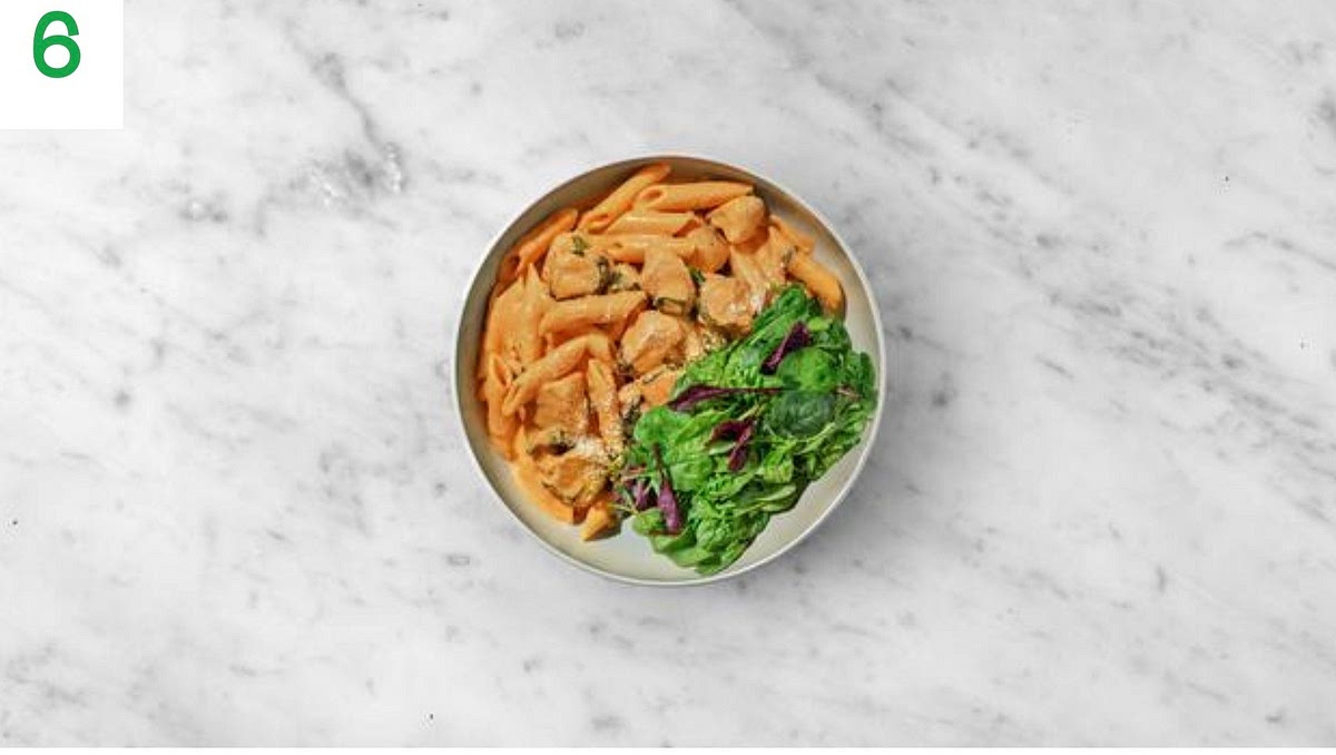 Add the cooked pasta to the creamy sauce and mix well to combine. Reheat until piping hot if needed.
Share the creamy Cajun pasta between your bowls.
Add the baby leaves alongside the pasta and drizzle over a little olive oil. Sprinkle over the remaining cheese to finish.