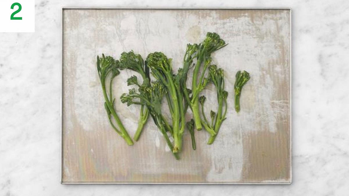 Meanwhile, halve any thick broccoli stems lengthways.
Pop the tenderstem broccoli onto a medium baking tray.
Drizzle with oil, season with salt and pepper, then toss to coat. Spread out in a single layer.
When the oven is hot, roast on the middle shelf until tender and crispy, 10-12 mins.