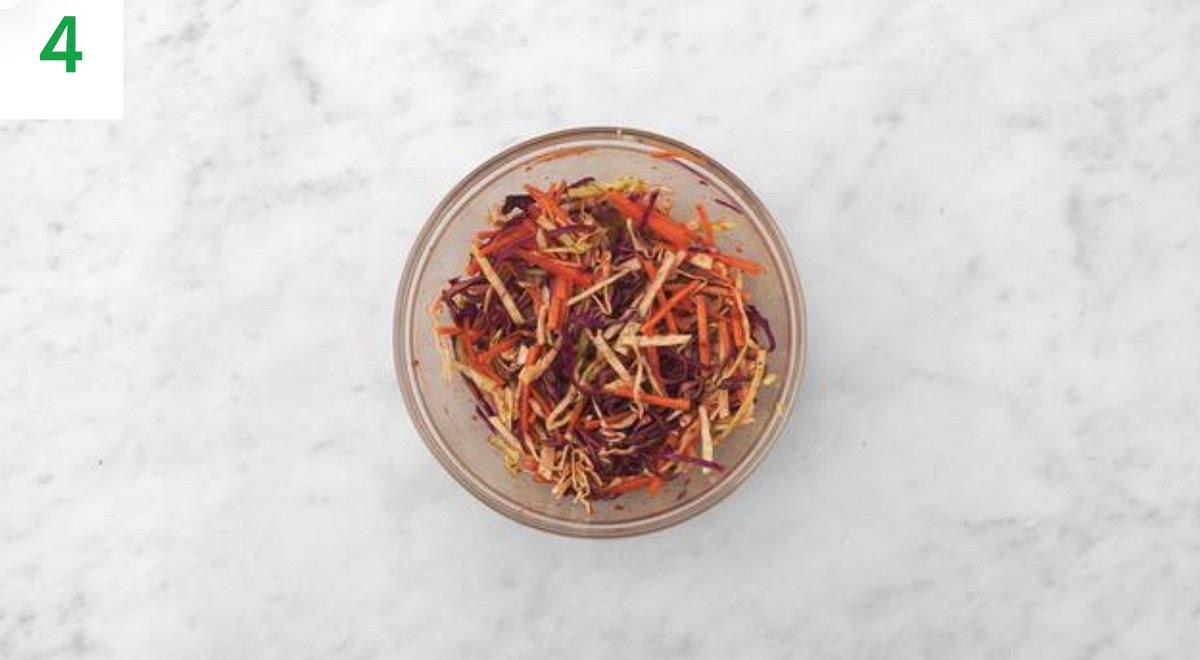 While the mushrooms fry, in a medium bowl, combine the rice vinegar, sambal and sugar for the pickle.
Stir in the sliced carrot and cabbage.
Season with salt and pepper. Set aside.