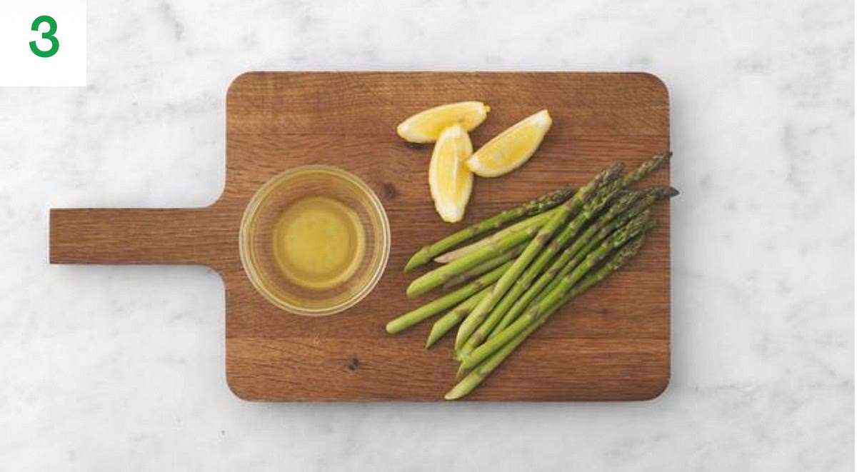 Bake the risotto on the middle shelf of your oven until the rice is cooked and the water has been absorbed, 25-30 mins.
In the meantime, trim the bottom 2cm from the asparagus and discard.
Cut the lemon into wedges.
In a large bowl, add half the lemon juice with the sugar and olive oil for the dressing. Season with salt and pepper, then set aside for later.