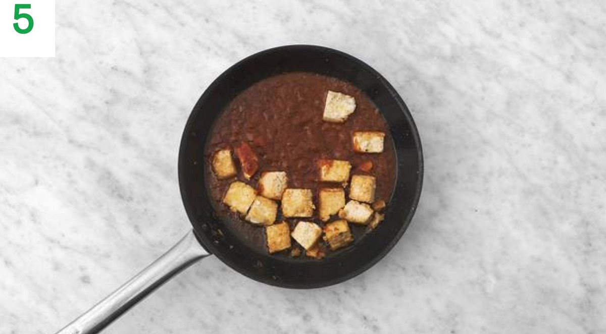 Put the frying pan back on high heat with a drizzle of oil.
Once hot, fry the tofu until slightly crispy, 8-10 mins.
Turn frequently to ensure it doesn't burn. Season with salt and pepper.
Add the peanut and sweet chilli sauce. Simmer until slightly thickened, 1-2 mins, then remove the pan from the heat.
Add a splash of water if it's a little thick. Taste and season with salt and pepper if you feel it needs it.
Add the tofu and sauce to the bowl with the cabbage and cucumber and mix together until combined.