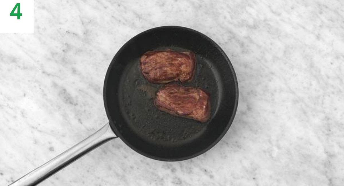Wipe out the (now empty) frying pan and return to high heat with a drizzle of oil. Season the lamb steaks with salt and pepper. TIP: Lamb steaks naturally vary in shape, so adjust the following timings depending on how you like yours cooked.
At the same time, put the broccoli and tomato tray onto the middle shelf to roast until the broccoli is tender and the tomatoes have so