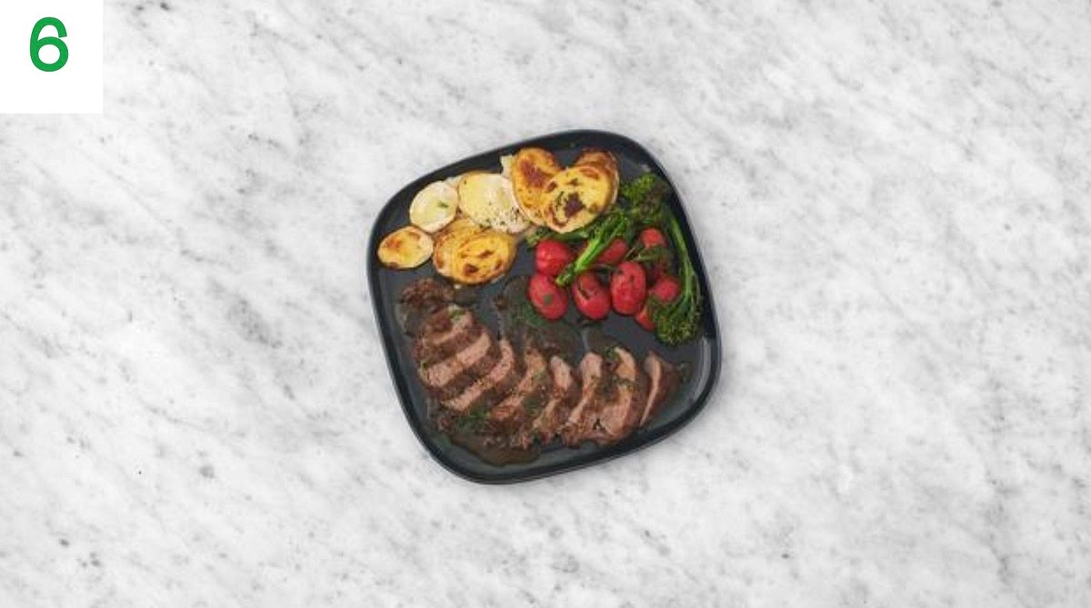 When everything's ready, thinly slice the lamb steaks and transfer to your plates. Spoon over the garlic butter sauce.
Serve the dauphinoise potatoes, roasted broccoli and tomatoes alongside.