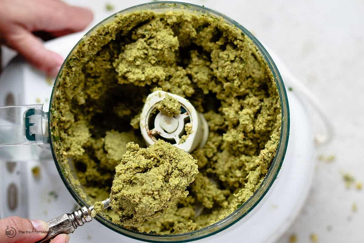 Add the chickpeas, herbs, onions, garlic and spices to the large bowl of a food processor fitted with a blade. Run the food processor 40 seconds at a time until all is well combined forming a the falafel mixture.