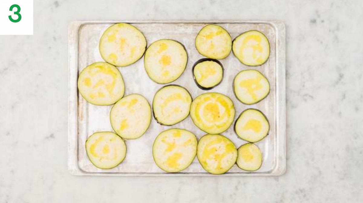 Meanwhile, trim the aubergine and slice into 1cm thick rounds.
Pop the aubergine rounds onto a large baking tray.
Drizzle with oil, season with salt and pepper, then toss to coat. Spread out in a single layer. TIP: Use two baking trays if necessary.
When the oven is hot, roast on the top shelf until soft and golden, 20-25 mins. Turn halfway through.
In the meantime, bring a large saucepan of water with ½ tsp salt to the boil for the broccoli.