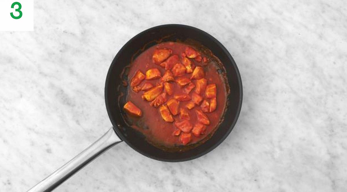 Meanwhile, peel and grate the garlic (or use a garlic press).
Cut the tomato into 1cm chunks.
Roughly chop the cranberries.
Once the chicken is cooked, stir in the garlic and harissa paste (add less if you'd prefer things milder).
Cook until fragrant, 1 min.