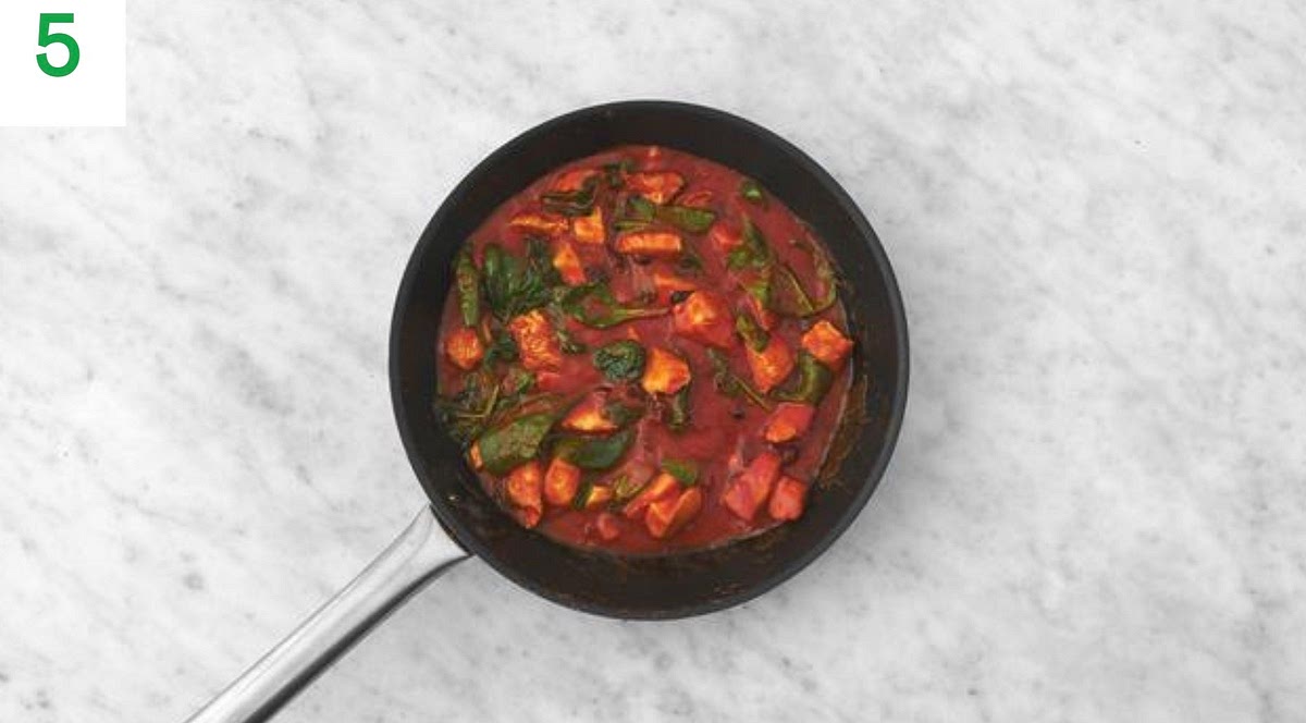 Once thickened, stir the spinach into the chicken pan a handful at a time until wilted and piping hot, 1-2 mins.
When ready, fluff up the bulgur with a fork and stir through the tomato chunks.