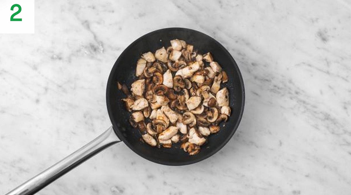 While the potatoes cook, heat a drizzle of oil in a large frying pan on high heat.
Once hot, add the diced chicken and sliced mushrooms to the pan. Season with salt and pepper.
Fry until the chicken is golden brown on the outside and cooked through, 8-10 mins.