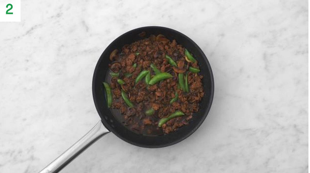 Next, reduce the heat to medium. Add the Indonesian style spice mix, ginger puree and young pea pods. Stir-fry, 1 min.
Stir in the miso, ketjap, soy, honey and water.