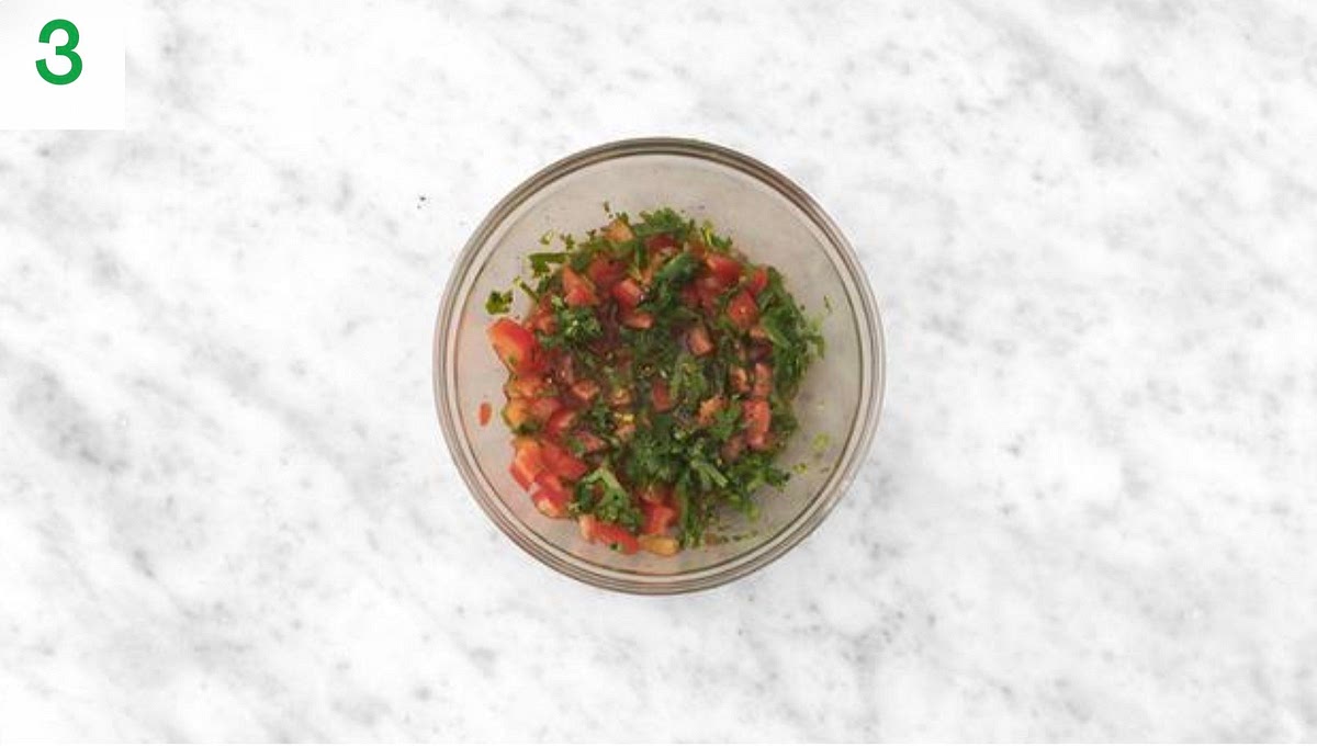 Meanwhile, cut the lime into wedges. Roughly chop the coriander (stalks and all).
Cut the tomatoes into small 1cm chunks and pop into a small bowl along with half the coriander.
Drizzle in some olive oil, squeeze in some lime juice, season with salt and pepper and mix together. Set your salsa aside.