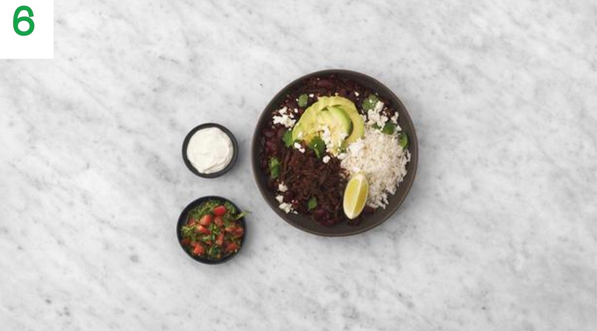 Share the rice between your bowls and spoon over the chilli.
Crumble on the Greek style cheese and sprinkle over the remaining coriander.
Fan the avocado slices out on top of the chilli. Pop any remaining lime wedges on top for squeezing over.
Serve the tomato salsa and soured cream on the side in small bowls for everyone to help themselves to.