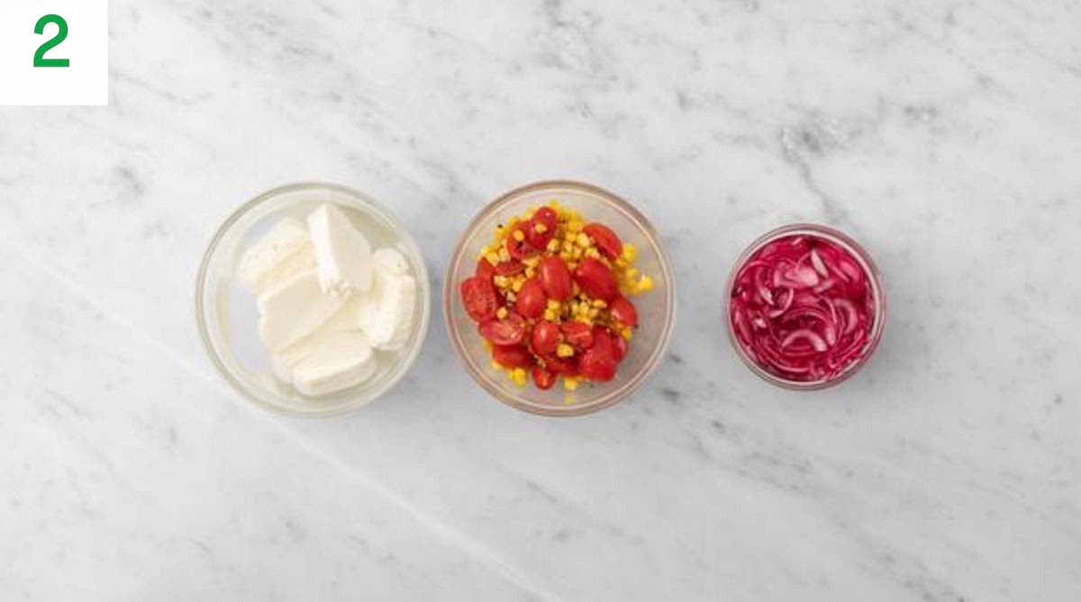 Meanwhile, drain the halloumi, then cut it into 3 slices per person. Place into a medium bowl of cold water and leave to soak.
Halve, peel and thinly slice the red onion. In a small bowl, combine the red onion, sugar for the pickle (see pantry for amount), the cider vinegar and a pinch of salt. Set aside to pickle.
Drain the sweetcorn in a sieve. Halve the tomatoes. Pop the corn and tomatoes into another medium bowl with a drizzle of oil. Season with salt and pepper, then set aside.