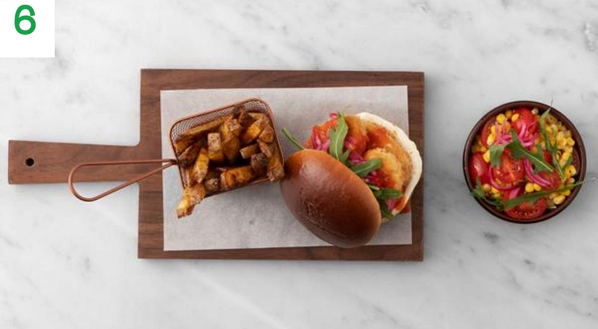 To build your burgers, spread the mayo (see pantry for amount) over the bun bases. Stack the halloumi on top, then drizzle over the buffalo sauce. Top with some of the rocket and pickled onion, then close with the bun lid.
Add any remaining rocket and pickled onion (including the pickling liquid) to the bowl of tomato and corn, then toss together.
Serve your craft burgers with the spiced fries and corn salad on the side.