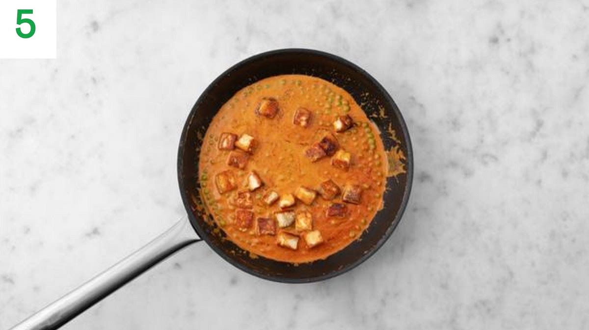Meanwhile, out the naans onto a baking tray. Sprinkle over the remaining garlic and drizzle over some oil.
Sprinkle with a little water and pop them into the oven to warm through, 2-3 mins.
Once the curry has thickened, stir the butter into your curry sauce until melted.
Add the spinach a handful at a time until wilted and piping hot, 1-2 mins. Taste and season with salt and pepper if needed.
Stir the cooked paneer through the sauce, then remove from the heat.