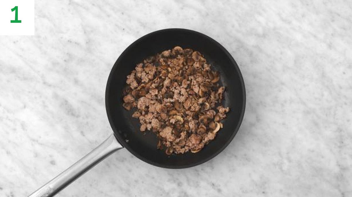 Peel and grate the garlic (or use a garlic press). Trim and thinly slice the spring onions.
Heat a large saucepan on medium-high heat (no oil).
Once hot, add the beef mince and mushrooms. Fry until the mince has browned, 5-6 mins. Use a spoon to break up the mince as it cooks.
When the mince has browned, drain and discard any excess fat. Season with salt and pepper.