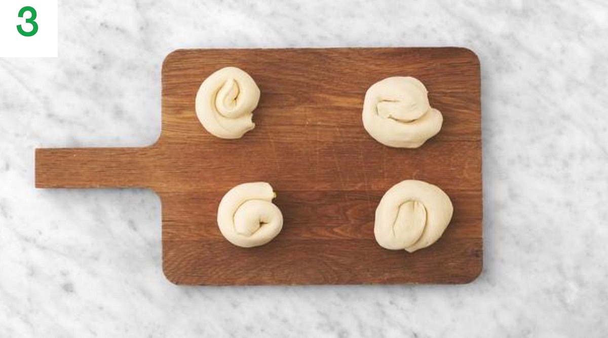 While the beef is braising, unroll the puﬀ pastry onto a clean, lightly floured surface.
Remove the paper and evenly sprinkle over most of the spring onion over the pastry. Set aside a small amount of the spring onion to use as a garnish.
Season the pastry with salt and pepper and tightly roll it back up. Cut it lengthways into 4 equal sized rolls.