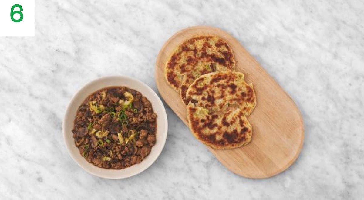 When everything's ready, share the braised beef between your serving bowls.
Serve the spring onion pastries alongside.
Sprinkle the remaining spring onion over the beef to finish.