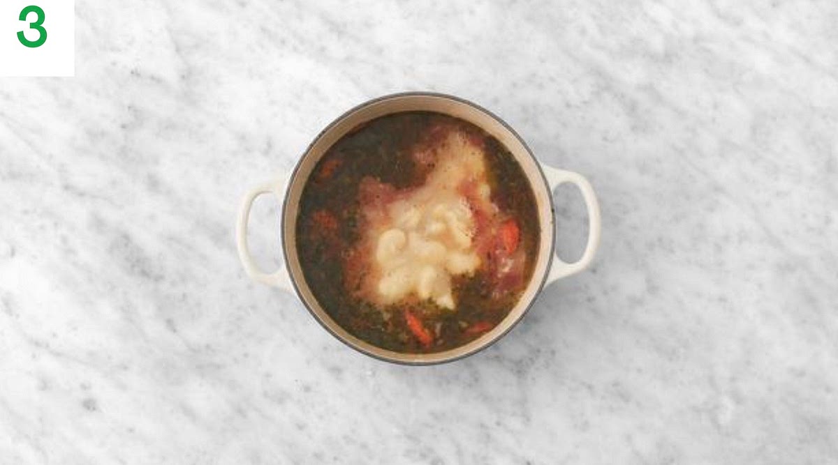 Return the pan (no need to clean) to medium-high heat with a drizzle of oil.
Add the bacon, carrot and onion and stir-fry until starting to so en, 5-6 mins.
Once sofened, add half the garlic and fry until fragrant, 1 min.
Once fragrant, stir in the mixed herbs, passata, white wine stock powder, sugar and water for the sauce (see pantry for both amounts). Stir in the butter beans and their liquid and bring to a boil.