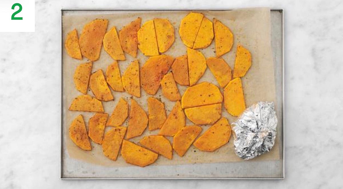 Halfway through cooking, add the salmon to the same tray, skin-side down. Season. Roast, 10-15 mins.
Meanwhile, halve, peel and thinly slice the red onion.
Halve the tomatoes and pop them onto a piece of foil with a drizzle of oil, then season with salt and pepper.
Fold the foil, sealing on all sides to create a parcel. Pop into the oven and roast until so