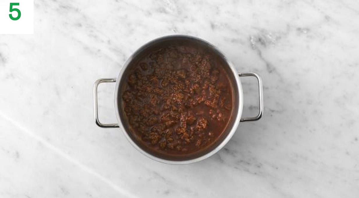 Once your chilli has thickened and the mince is cooked, stir through the BBQ sauce. Taste and season with salt and pepper if you feel it needs it.
Once the potatoes are ready, remove them from your oven.
Add a knob of butter (if you have any) to the cut sides of the potatoes. Roughly mash it into the potato with a fork.