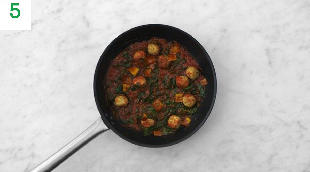 Once your harissa sauce has thickened, add the spinach to the pan a handful at a time until wilted and piping hot, 1-2 mins.
Lower the heat to medium and add the falafels to the sauce, carefully stirring to coat. Season with salt and pepper.
Simmer gently until cooked through, 5 -6 mins.
Add the cooked sweet potato and butter (see pantry for amount) to the sauce. Stir gently until the butter has melted.