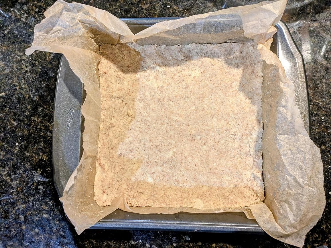 The dough should look a little dry, but come together when pressed. Add your crust ingredients into the pan. Evenly press down into all sides. Bake at 350F for about 20 minutes, or until lightly browned. Let cool totally before adding the filling on top, or you can rip the base when spreading on the filling