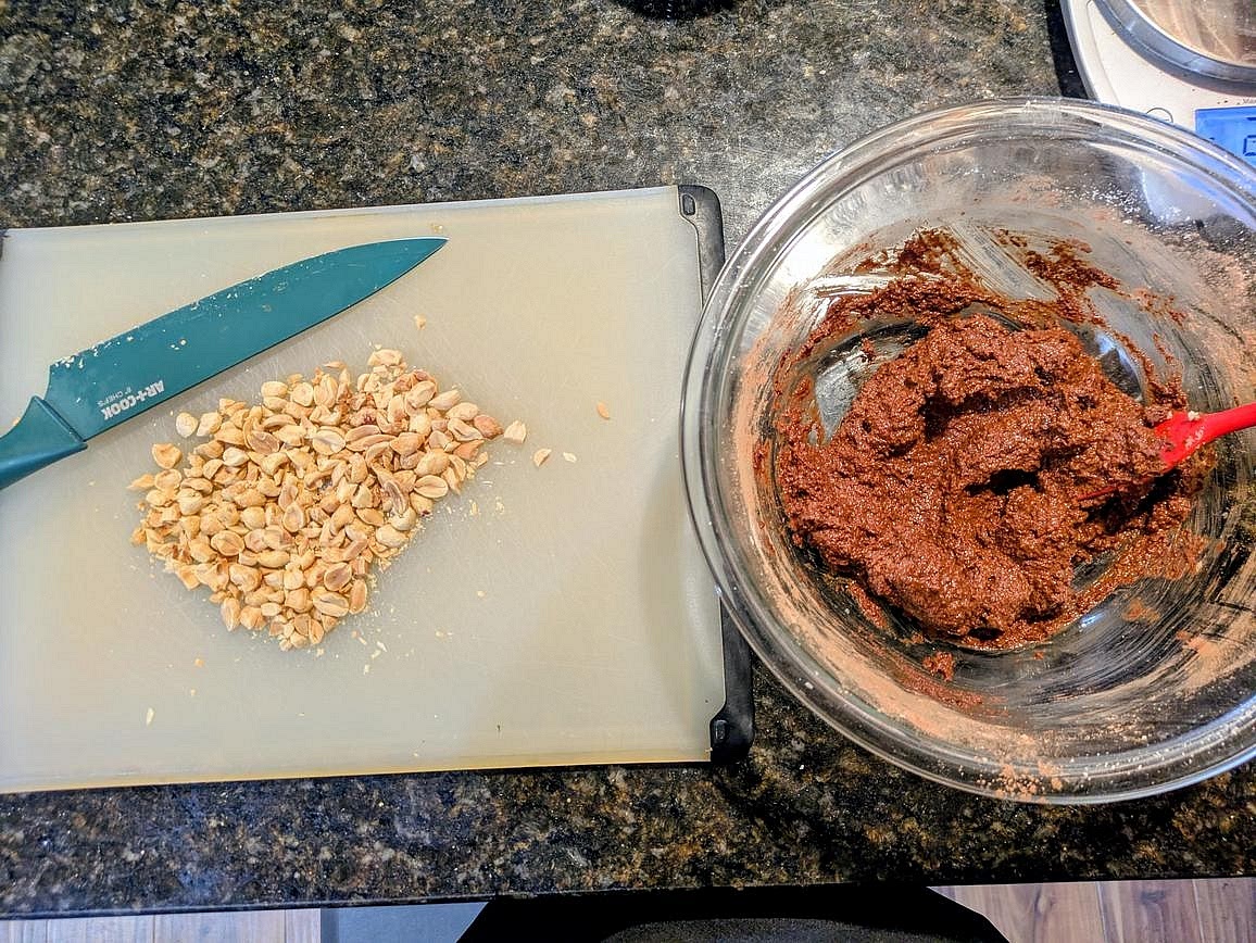 Meanwhile, rinse out your bowl, and mix together the filling ingredients with a silicone spatula - carob, powdered peanut butter, cinnamon, salt, vanilla, liquid monk fruit, and applesauce. Roughly chop your peanuts