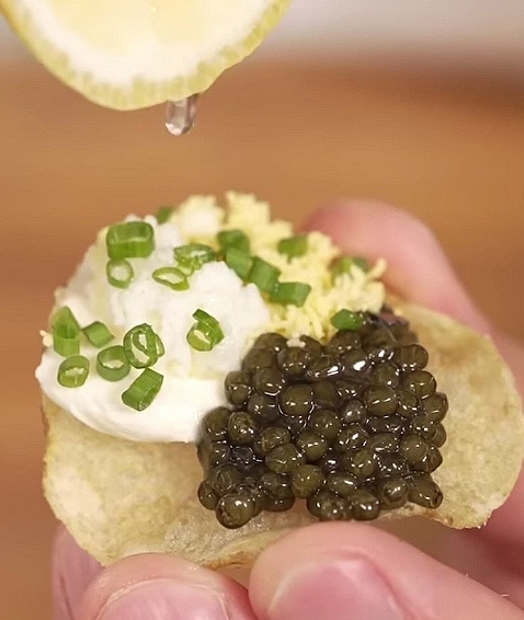 Assemble the Toppings: * Place a small dollop of creme fraiche onto a single chip.
​Add a generous spoonful of caviar next to the cream.
​Top with a pinch of the grated egg white and egg yolk.
​Garnish with the minced chives.