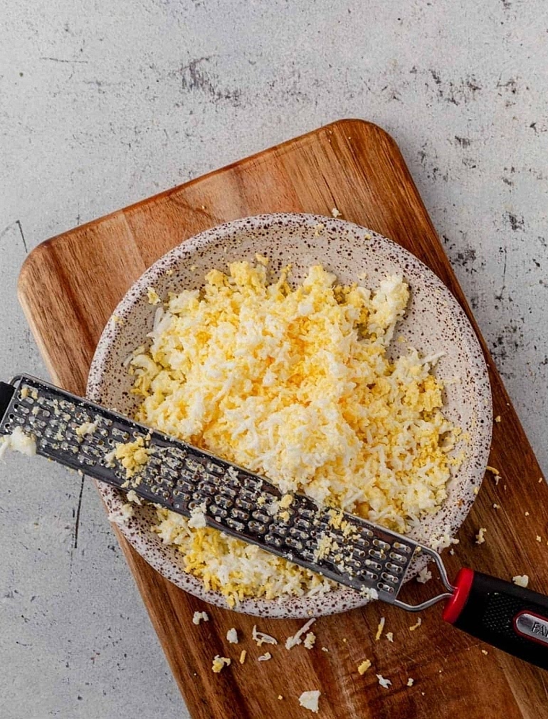 Grate the Eggs: Separate the cooked egg whites from the yolks and push each through a fine-mesh strainer to create a light, fluffy texture.