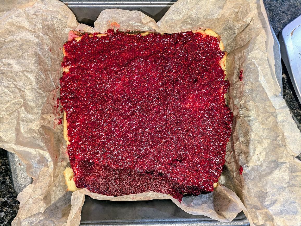 Once the cookie layers and the jam have totally cooled, spread half your jam (about 1/2 cup, 150 g) on top of the red layer. Place the yellow layer on top of the red layer, and spread the other half of the jam (1/2 cup, 150 g) on top of the yellow layer. Place the green layer on top