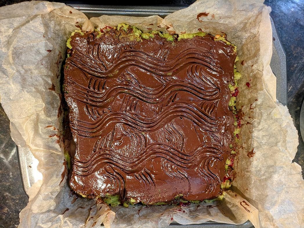 The next day, remove the weight and top layer of parchment. Melt half of your coconut oil in a small bowl, and mix with half your cocoa powder and half your granulated sweetener with a silicone spatula. Spread onto the top layer of the cake. Optionally draw straight or curved lines using a fork. Chill in the refrigerator until the chocolate is firm, at least 30 minutes