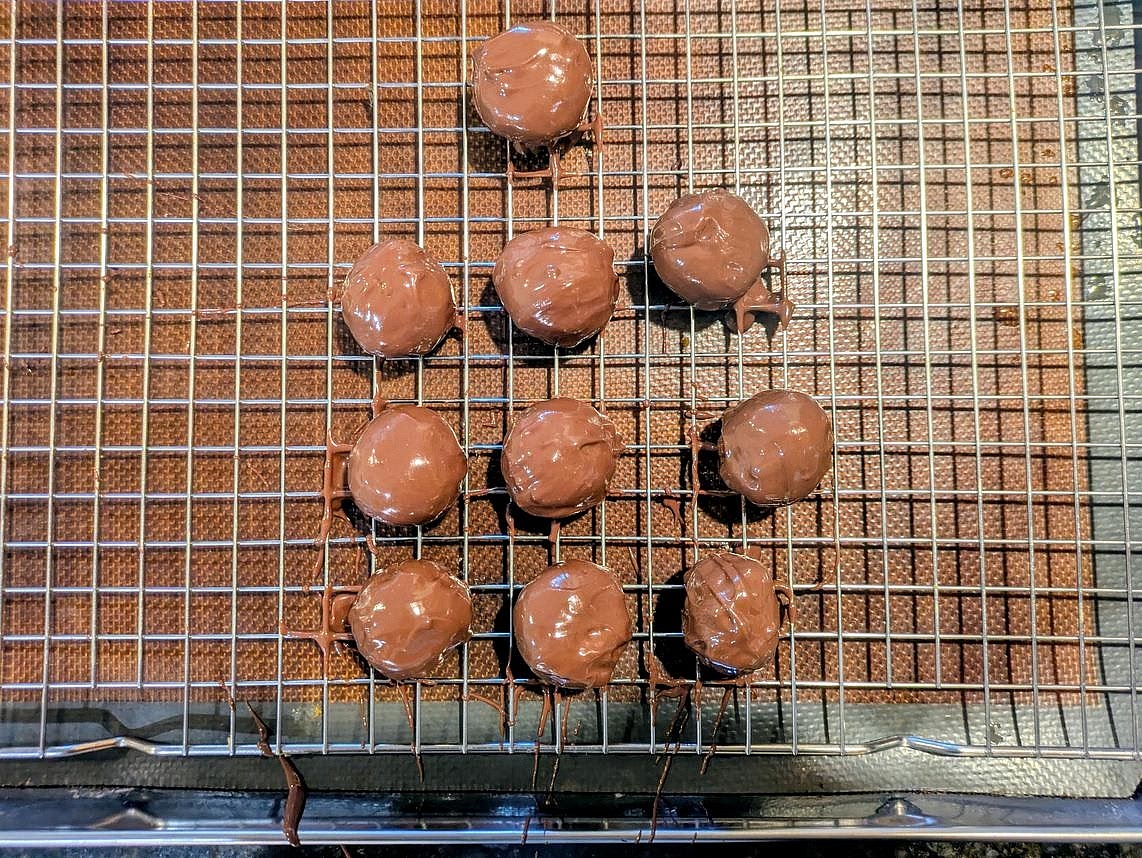 Using 2 forks, coat the pistachio dough in the chocolate, and add to the wire rack. Repeat with all the truffles